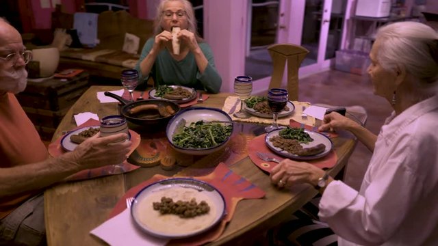 Steadicam orbit around a table with a family starting their dinner in a dining room in a house.