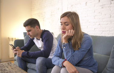 young attractive couple in relationship problem with internet mobile phone gambling addict boyfriend ignoring sad neglected and bored girlfriend