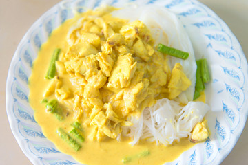 Rice vermicelli in green curry with Clown featherback, Clown knifefish and vegetables with Long bean and hoary basil on wooden table the traditional delicious Thai food.