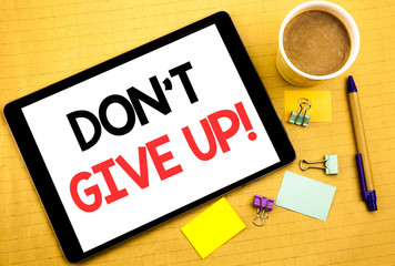 Conceptual hand writing text caption showing Don t Give Up. Business concept for Motivation Determination, Written on tablet laptop, wooden background with sticky note, coffee and pen