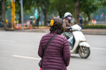 People walking across a street while motorbikes keep running on street in Hanoi, Vietnam. Closeup
