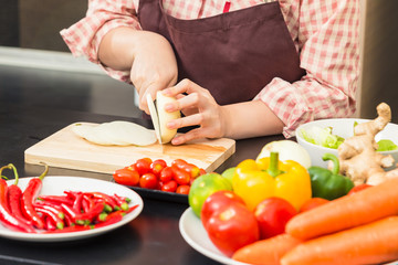 Female hands cutting green lime on wooden cutting board in her home kitchen