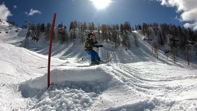 Freestyle skiing. Little boy jumping in a snowpark. A 5 year old child enjoys a winter holiday in the Alpine resort. Stabilized shot. Slow motion.
