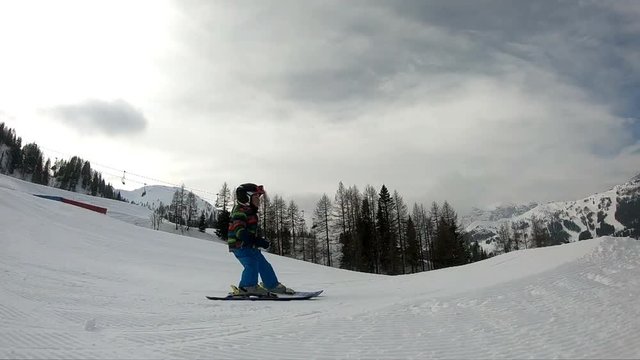 Freestyle skiing. Little boy jumping in a snowpark. A 5 year old child enjoys a winter holiday in the Alpine resort. Stabilized shot. Slow motion.

