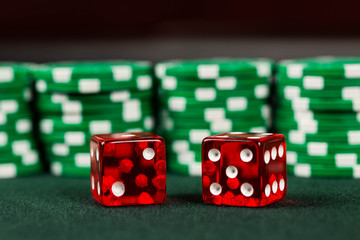 Dice on a poker table with gambling poker chips stacked behind representing a win at a casino.