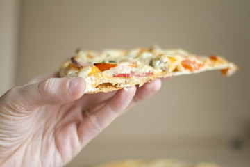 a slice of pizza in hand