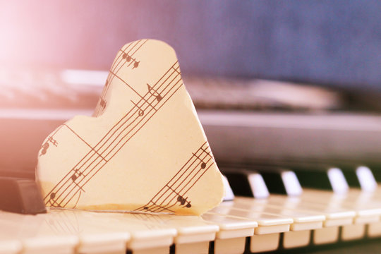 close-up music score on piano keyboard, heart of paper