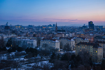 Fototapeta na wymiar A winter evening sets over Vienna as the sun disappears and the many windows of the city begin to light up