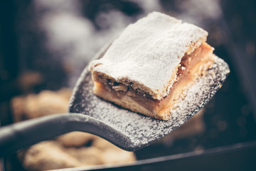 Applying delicious apple cake with a spatula in the kitchen by a confectioner.