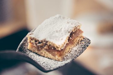 Applying delicious apple cake with a spatula in the kitchen by a confectioner.