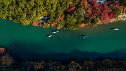 Zelfklevend Fotobehang Aerial view Boatman punting the boat for tourists to enjoy the fall color season view of Hozu river in Togetsukyo bridge is one of the most scenic Arashiyama in Kyoto City, Arashiyama, Kyoto, Japan. © Kalyakan