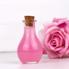Obraz na płótnie Canvas rose essential oil bottle blurred rose flower white background square