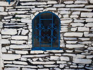 old blue window on white stone wall. Aegean style