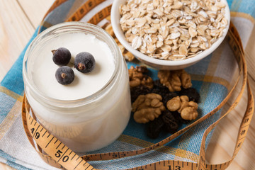 yogurt in a jar, oat flakes and nuts, a measuring tape, the concept of a healthy diet
