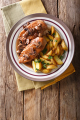 Chicken in Marsala sauce with mushrooms and fried potatoes close-up on a plate. Vertical top view