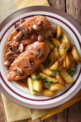 Delicious food: chicken breast in Marsala sauce with mushrooms and fried potatoes close-up. Vertical top view