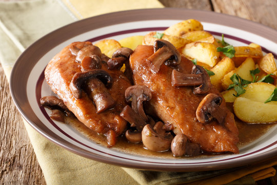 Delicious food: chicken breast in Marsala sauce with mushrooms and fried potatoes close-up on a plate on a table. horizontal