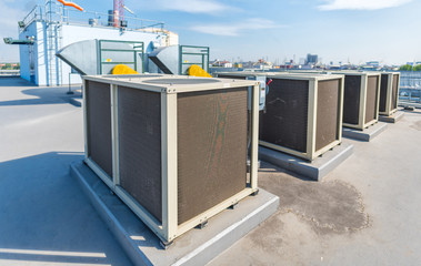 Air compressor machine part of air conditioner system on roof deck with sky background.