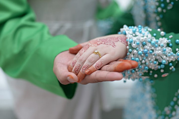 Bride & groom holding hands showing off the beautiful henna art in a Malaysian wedding.