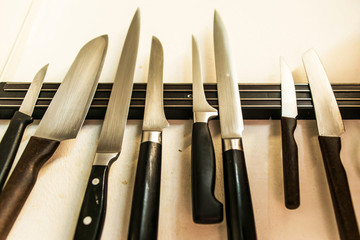 set of high quality kitchen cook knives tools on a magnet board hanging on the wall