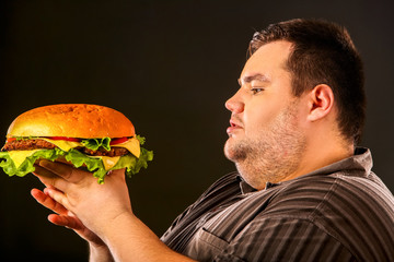 Man eating fast food hamberger. Fat person made great huge hamburger and admires him, intending to...