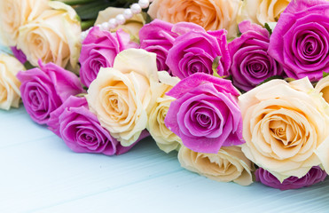 Beautiful roses on a turquoise (blue) background. Roses and pearls on a wooden background