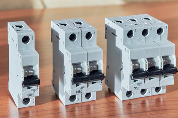 Three modular electrical circuit breakers on the table. The switch is single-pole, double-pole and three-pole. Protection of electrical wiring of household or home use. Distribution of electricity.