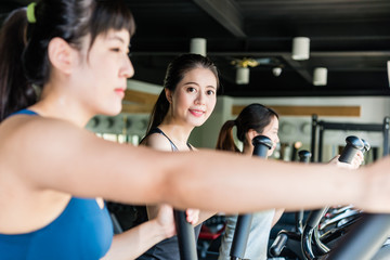Fototapeta premium Positive female training on elliptical trainers