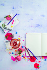 Feminine flat lay with tea, sweets and open book with empty pages. Colorful party background with confetti. Planning concept with copy space.