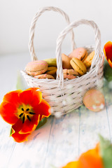 Fototapeta na wymiar Blossoming tulips with macaroons on a light wooden background. Still life, spring concept