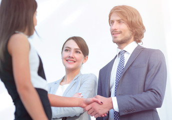 Businesspeople  shaking hands against room with large window loo