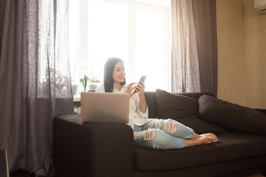 Young creative woman sitting in the bed with laptop. Casual blogger woman at home