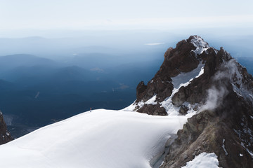 Steam rises from volcanic vents on the towering cliffs of Mt Hood on a snowy fall day