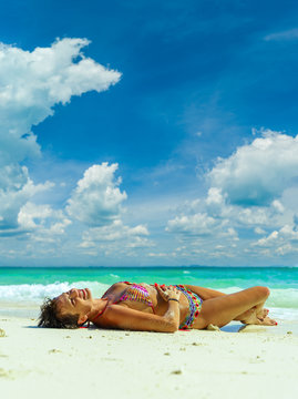 Cute woman relaxing on the summer tropical beach.  White sand, blue sky and crystal sea of tropical beach. Vacation in Paradise. Ocean beach relax, travel to islands