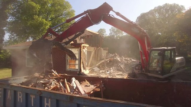 Excavator Filling Dumpster With House Debris