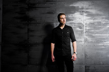 Studio portrait of stylish man wear on black shirt against steel wall.
