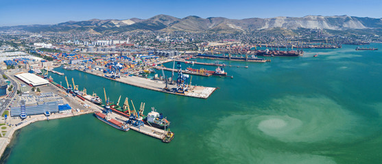 Panoramic aerial view of the international sea port of Novorossiysk. Port cranes, containers and cargo ships.