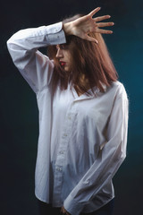 Girl, when no one sees reveals their real beauty. A beautiful young brunette with gorgeous hair behind a wet glass in a white shirt, passionately posing