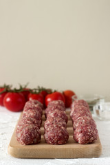 Raw meatballs, tomatoes and spices on a white concrete background. Rustic style.