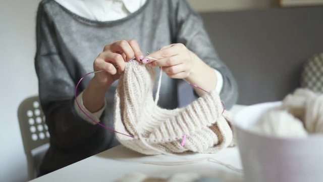 Young woman knitting thread at table. Close up of female hands knitting needles wool clothes. Woman hobby