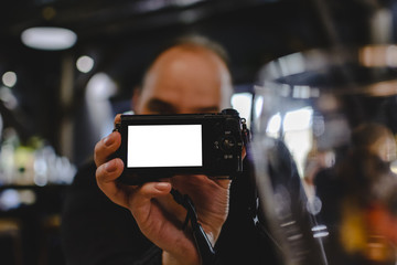 unknown blurry man holding a camera with blank space for text on screen.