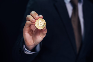 Close-up of businessman showing and holding bitcoin sign of coin - indicating crypto currency and future of digital financial banking trade