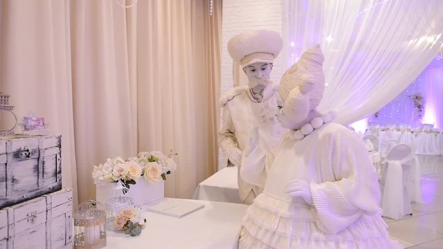 performance of mimes in white vintage clothes in the banquet hall