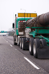 Fototapeta na wymiar Big rig semi truck transporting oversize pipe cargo on the straight highway