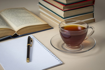 Tea, books and notebook on white table