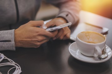 mobile phone hands in the cafeteria with the cup of coffee