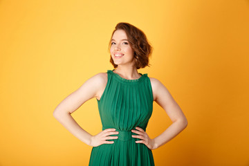 portrait of smiling woman akimbo isolated on orange