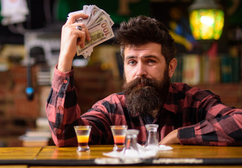 Hipster holds money, counting cash to buy more alcohol.