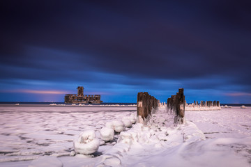 Frozen Baltic sea and ruins old military building at night in Babie Doly, Gdynia, Poland