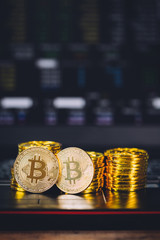 Bitcoin coins pile and two bit coins sitting in front with stock index graph chart digital background. Concept of Bitcoin and virtual currency and blockchain technology
